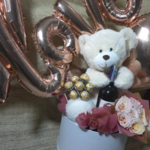 Cilindro en rosas, chocolates Ferrero Rocher, botella de Bailey's, peluche y globos
