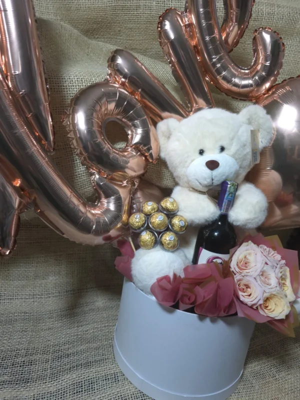 Cilindro en rosas, chocolates Ferrero Rocher, botella de Bailey's, peluche y globos